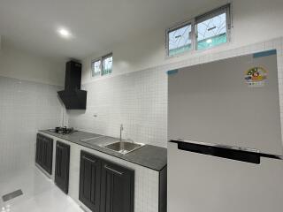 Modern kitchen with black cabinets, stainless steel sink, and a refrigerator.