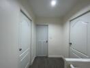 A well-lit hallway with three doors and wooden flooring