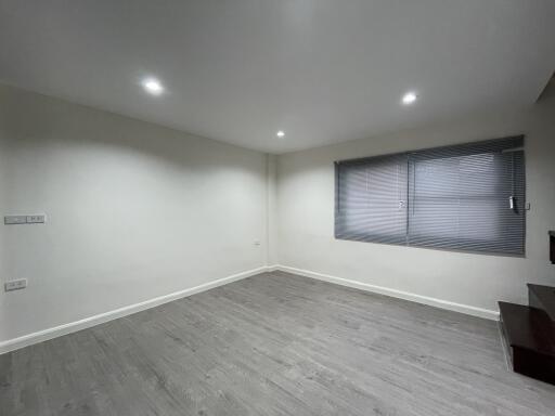 Empty living room with gray wooden flooring and window with blinds