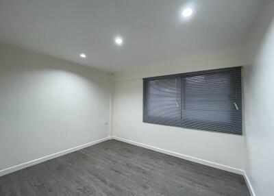 Spacious empty bedroom with wooden flooring and ceiling lights