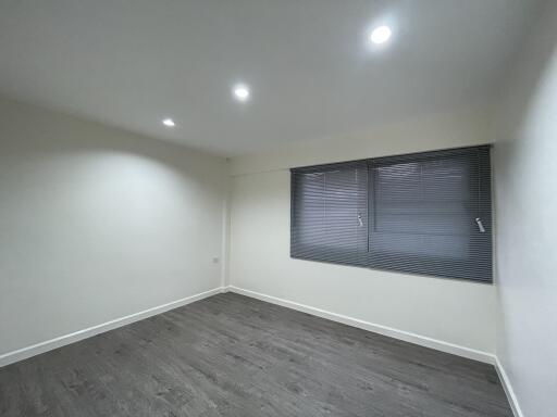 Spacious empty bedroom with wooden flooring and ceiling lights