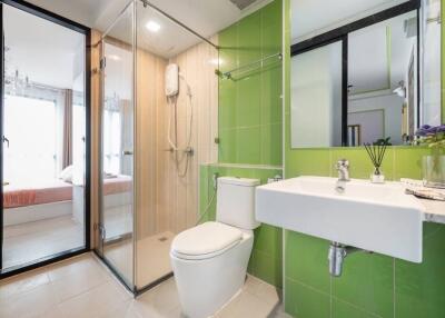 Modern bathroom with green tiles, glass shower, and white fixtures