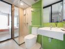 Modern bathroom with green tiles, glass shower, and white fixtures