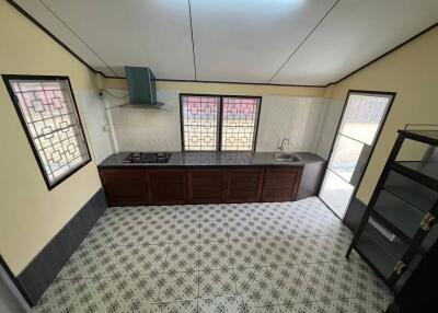 Modern kitchen with tiled floor, stove, sink, and windows