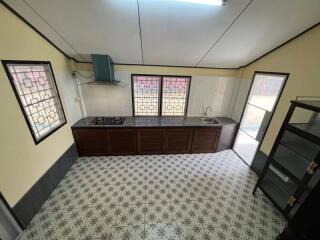 Modern kitchen with tiled floor, stove, sink, and windows