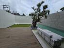 Modern outdoor space with wooden deck, green lawn, and a pool with a tree