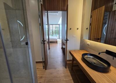 View of a bedroom from an adjoining bathroom with wooden flooring and natural light.