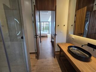 View of a bedroom from an adjoining bathroom with wooden flooring and natural light.