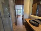 View of a bedroom from an adjoining bathroom with wooden flooring and natural light.