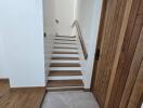 Wooden staircase with railing and adjacent wooden door