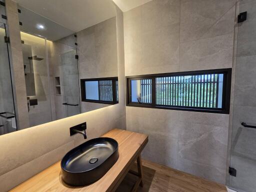 Modern bathroom with black fixtures and wooden countertop