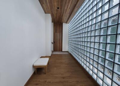 Hallway with wooden flooring, glass block wall, and wooden ceiling