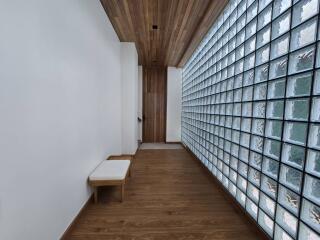 Hallway with wooden flooring, glass block wall, and wooden ceiling