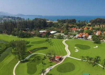 Aerial view of a luxurious golf course and resort with ocean in the background