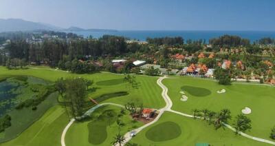 Aerial view of a luxurious golf course and resort with ocean in the background