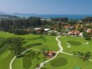 Aerial view of a luxurious golf course and resort with ocean in the background