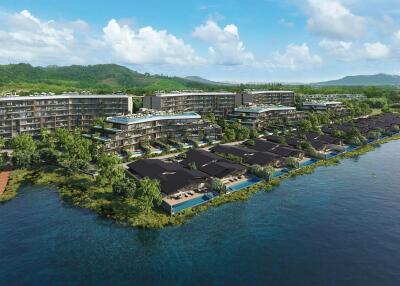 Aerial view of a waterfront residential complex with greenery and mountains in the background