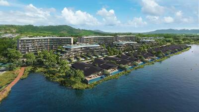 Aerial view of a waterfront residential complex with greenery and mountains in the background