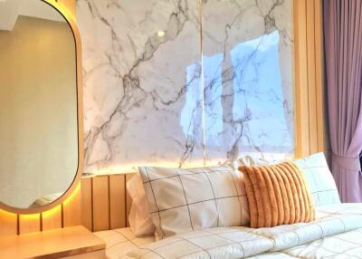 Modern bedroom with illuminated marble wall and cozy bedding