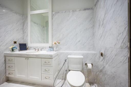 Well-lit bathroom with white marble walls and modern fixtures