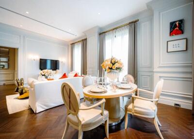 Elegant living room with dining area, featuring classic decor, large windows, and hardwood floors