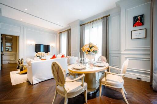 Elegant living room with dining area, featuring classic decor, large windows, and hardwood floors