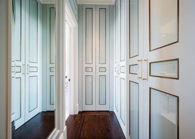 Spacious walk-in closet with ample storage space featuring white paneled doors and gold accents.