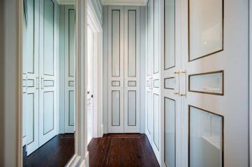 Spacious walk-in closet with ample storage space featuring white paneled doors and gold accents.