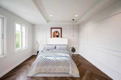 Modern bedroom with white walls, wooden floor, and a large bed