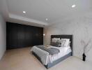 Modern bedroom with bed, black wardrobe, and accent lighting