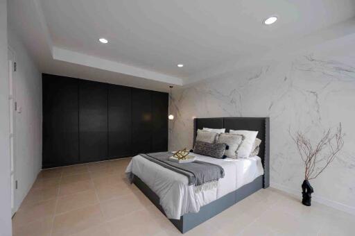 Modern bedroom with bed, black wardrobe, and accent lighting