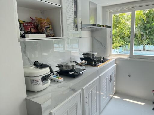 Modern kitchen with white cabinets, countertop appliances, and a large window