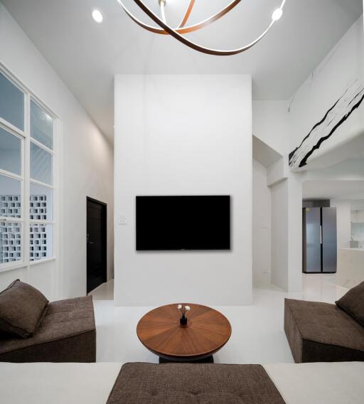 Modern living room with minimalist design, featuring a wall-mounted TV and contemporary furniture.