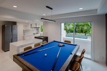 Modern living area with pool table and kitchen overlooking a garden