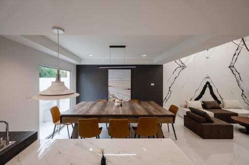 Modern dining area with a large wooden table, stylish lighting, and a partial view of the living room