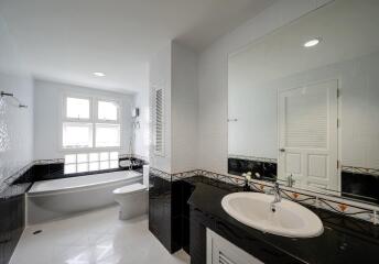 Modern bathroom with white and black tiles, large mirror, and a bathtub