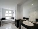 Modern bathroom with white and black tiles, large mirror, and a bathtub