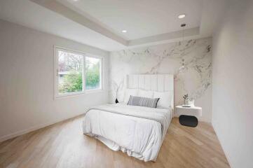 Modern bedroom with large window and marble accent wall