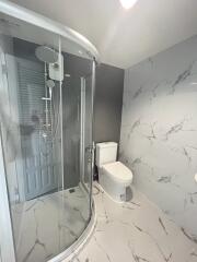 A modern bathroom with a glass-enclosed shower and marble tiles