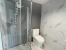 A modern bathroom with a glass-enclosed shower and marble tiles