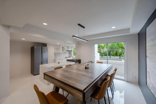 Modern dining area with large wooden table and adjoining kitchen