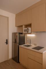 Modern kitchen with wooden cabinets, refrigerator, and microwave