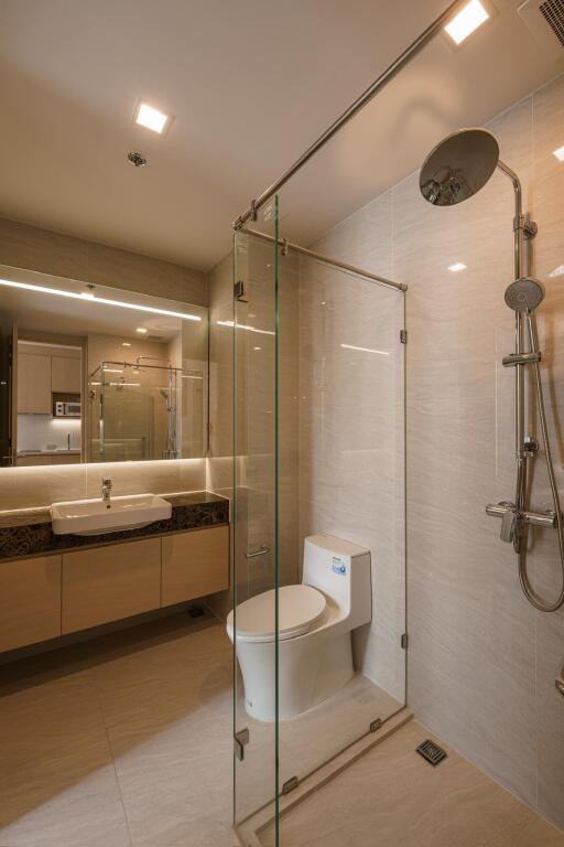 Modern bathroom with glass shower, vanity sink, and toilet