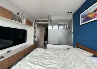 Modern bedroom with a TV, glass partition, and wall art