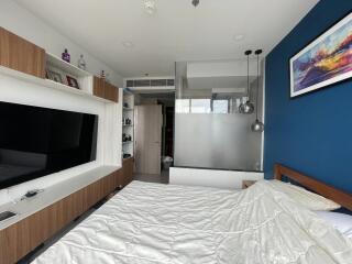 Modern bedroom with a TV, glass partition, and wall art