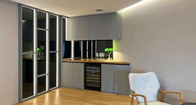 Modern compact kitchen with wooden countertop, gray cabinets, and wine cooler