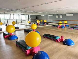 Spacious exercise room with equipment, large mirrors, and wooden flooring