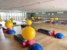 Spacious exercise room with equipment, large mirrors, and wooden flooring