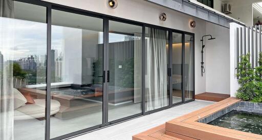 Modern living space with glass doors leading to a terrace featuring greenery and a small pool