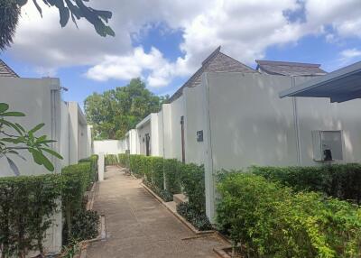 Outdoor view of the property with white buildings and green shrubs